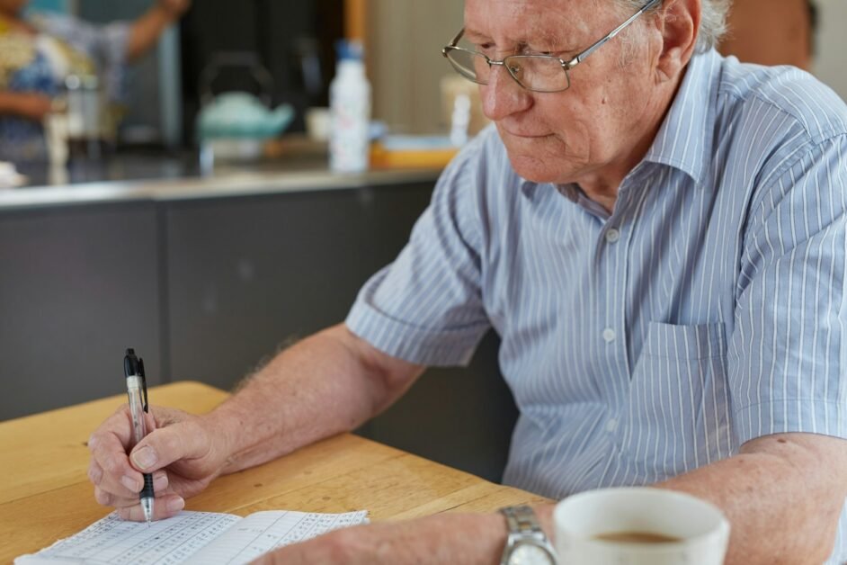 a man sitting at a table writing on a piece of paper